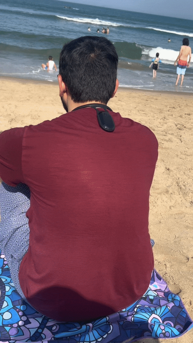 Man sitting on beach wearing R’LIEF smart posture corrector, demonstrating discreet all-day use in a relaxed outdoor setting